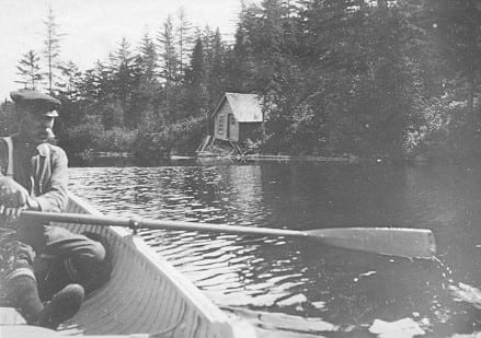 black and white photo of man paddling canoe in river