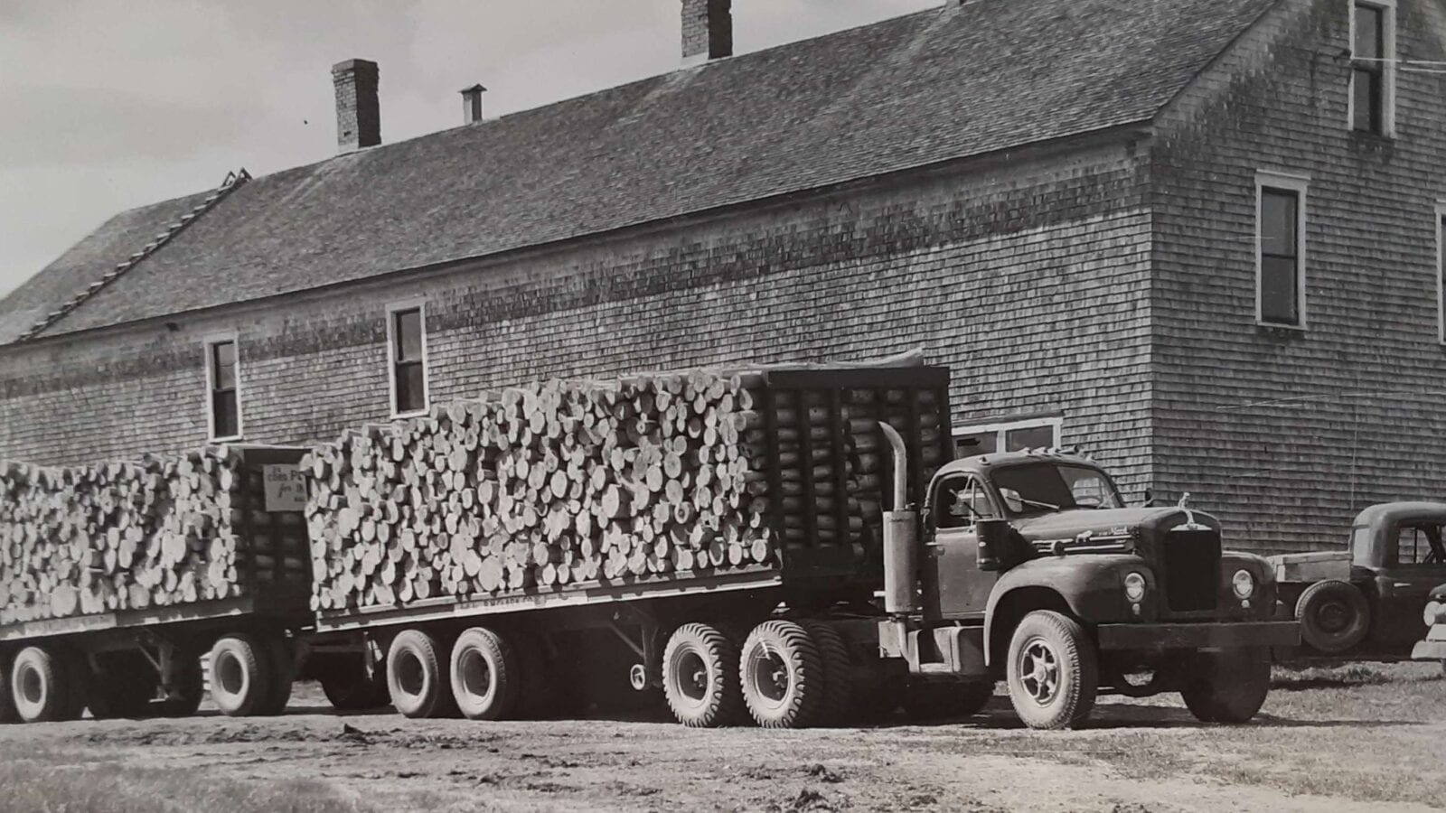 black and white photo of logging truck full of logs